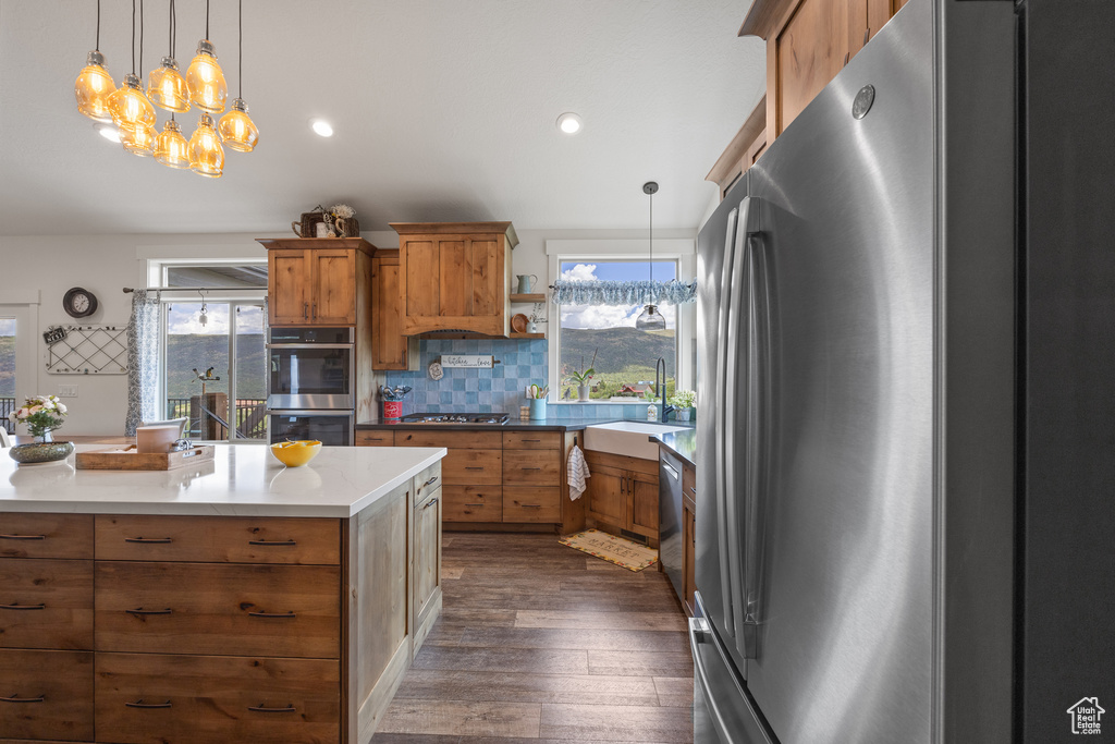 Kitchen with tasteful backsplash, stainless steel appliances, dark wood-type flooring, and decorative light fixtures