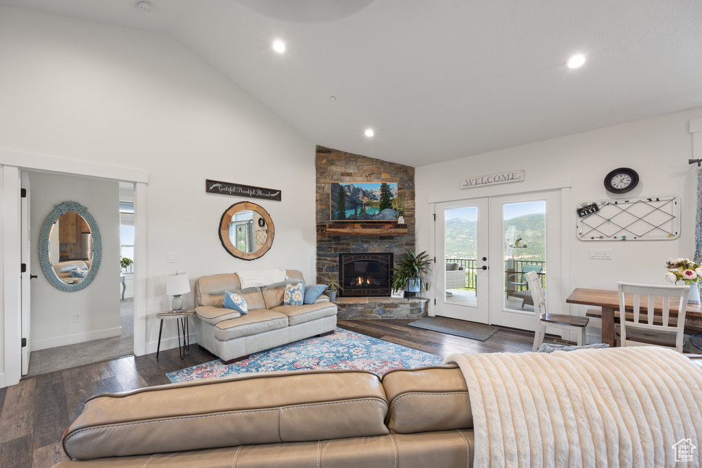 Living room featuring a stone fireplace, high vaulted ceiling, dark hardwood / wood-style flooring, and french doors