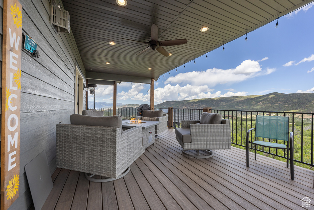 Deck with ceiling fan, a mountain view, and an outdoor fire pit