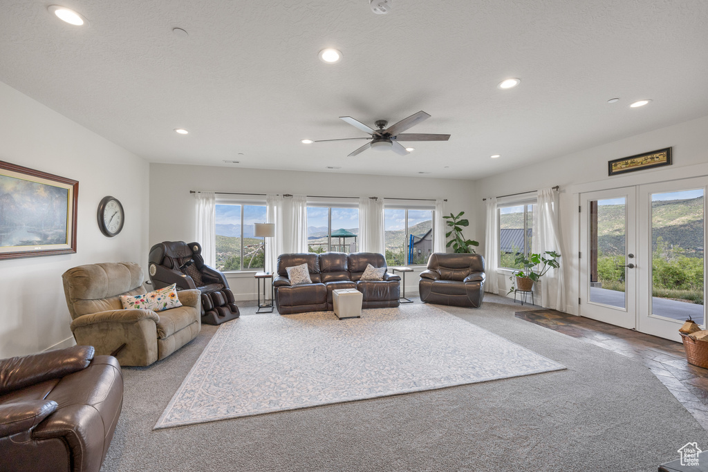 Carpeted living room with ceiling fan, french doors, and a healthy amount of sunlight