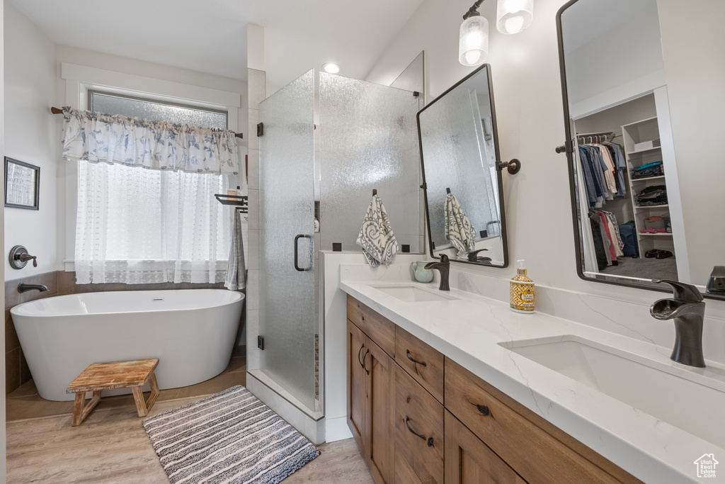 Bathroom with separate shower and tub, double sink vanity, and wood-type flooring