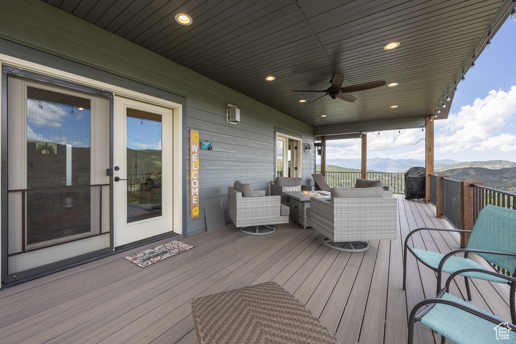 Wooden deck with ceiling fan, an outdoor hangout area, and a mountain view