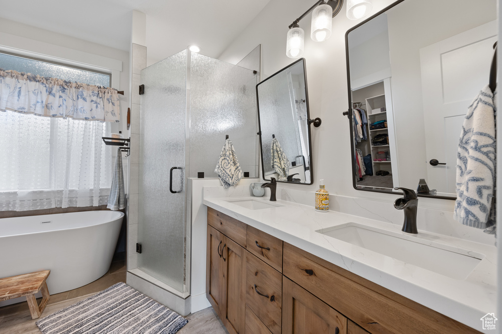 Bathroom featuring shower with separate bathtub and double sink vanity