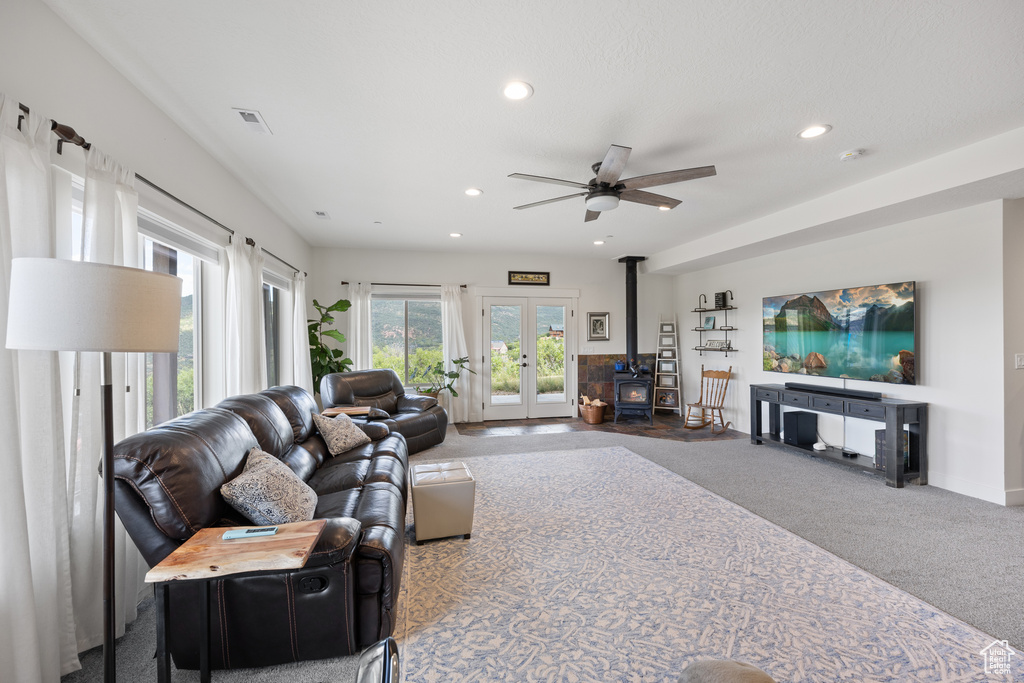 Living room with ceiling fan, french doors, carpet floors, and a wood stove