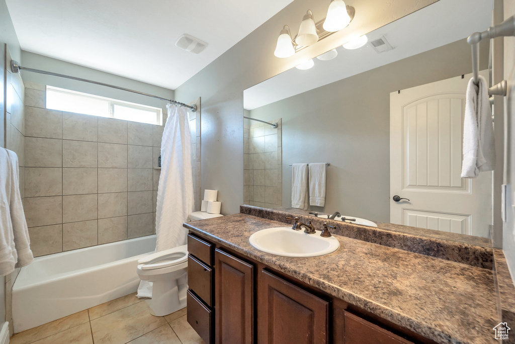 Full bathroom featuring shower / bath combination with curtain, toilet, vanity, and tile patterned floors