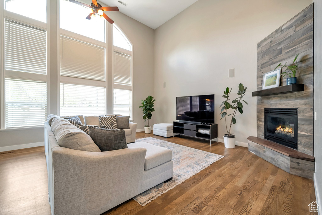 Living room featuring ceiling fan, high vaulted ceiling, hardwood / wood-style flooring, and a tiled fireplace