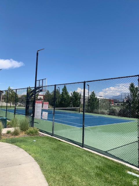 View of tennis court with a yard and basketball court