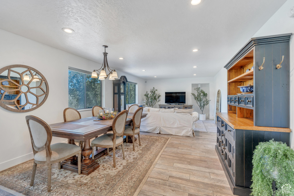 Dining area with a textured ceiling, a chandelier, and light wood-type flooring