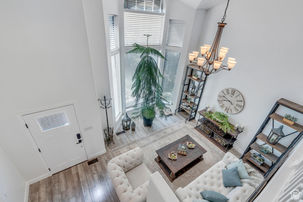 Living room with a towering ceiling, light hardwood / wood-style flooring, and a chandelier