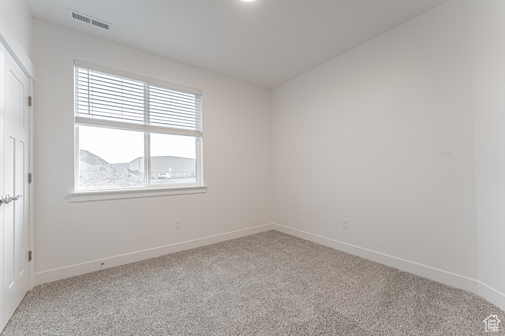 Carpeted spare room featuring visible vents and baseboards