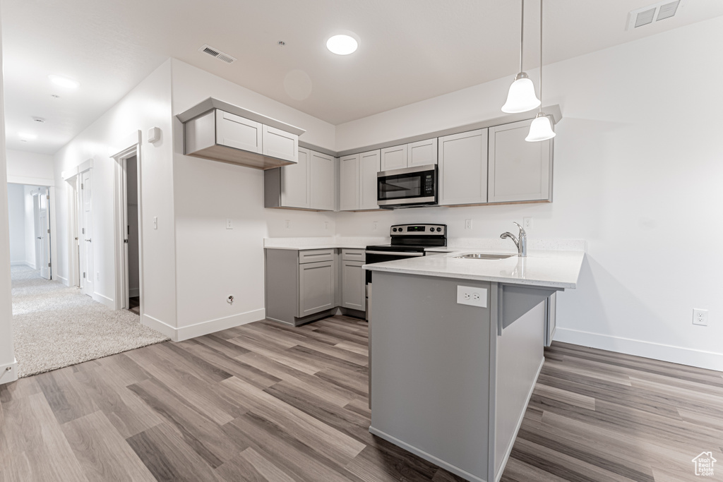 Kitchen with visible vents, appliances with stainless steel finishes, a peninsula, and gray cabinets