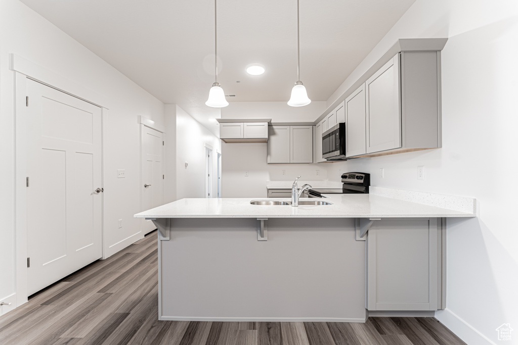 Kitchen featuring a peninsula, range with electric cooktop, a sink, light countertops, and stainless steel microwave