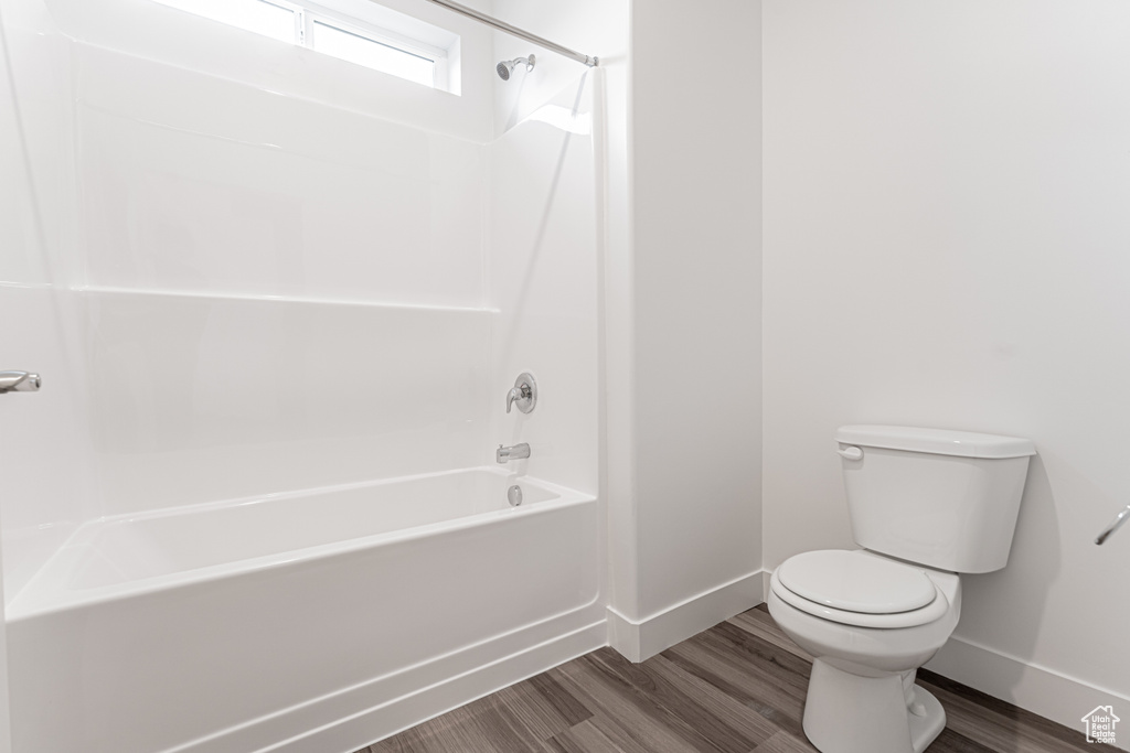 Full bathroom with toilet, wood finished floors, and baseboards