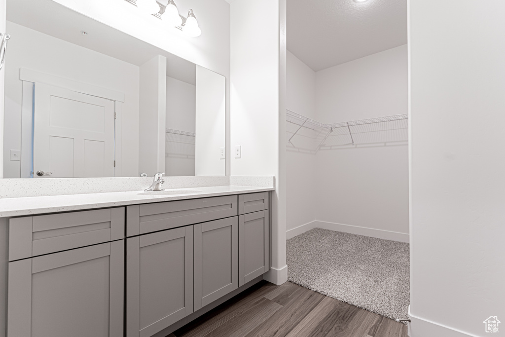 Bathroom featuring a walk in closet, baseboards, wood finished floors, and vanity