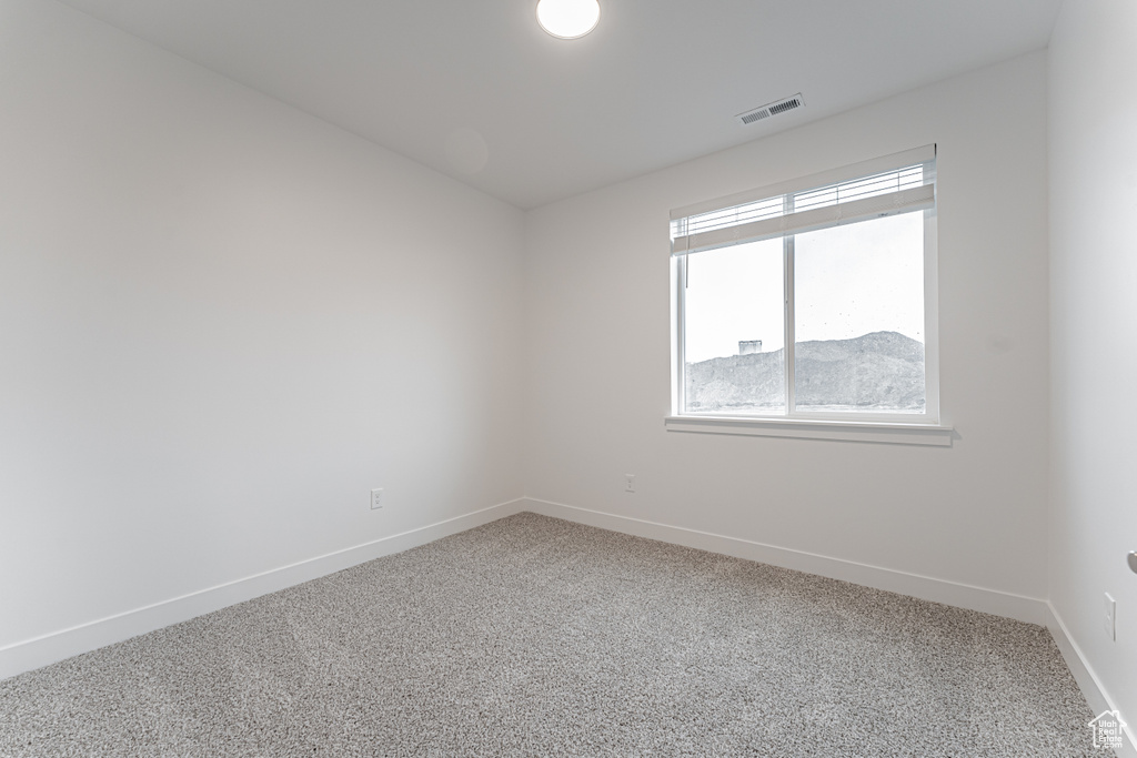Spare room featuring visible vents, carpet floors, and baseboards