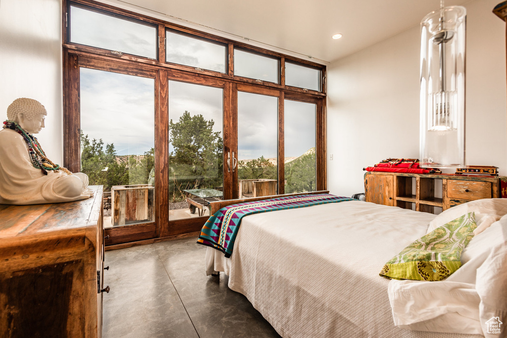 Bedroom with multiple windows, access to outside, and concrete floors