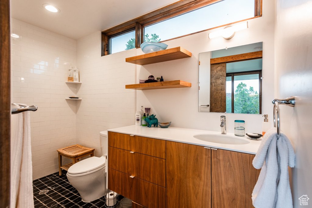 Bathroom featuring a wealth of natural light, toilet, tile patterned floors, and vanity