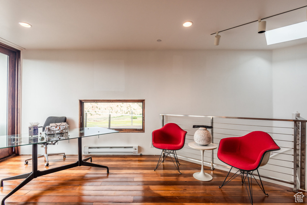 Sitting room with track lighting, hardwood / wood-style flooring, a skylight, and a baseboard radiator