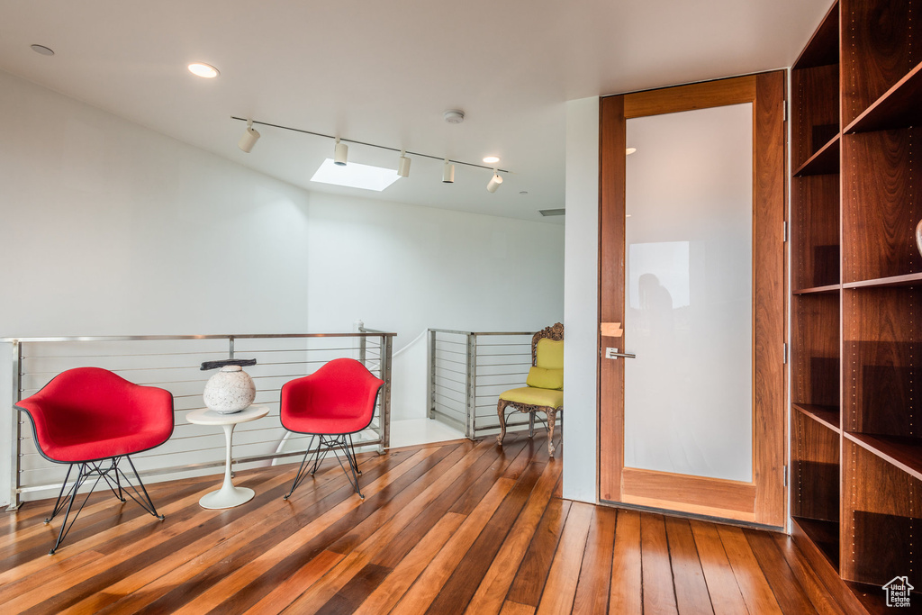 Living area featuring rail lighting, a skylight, and hardwood / wood-style floors