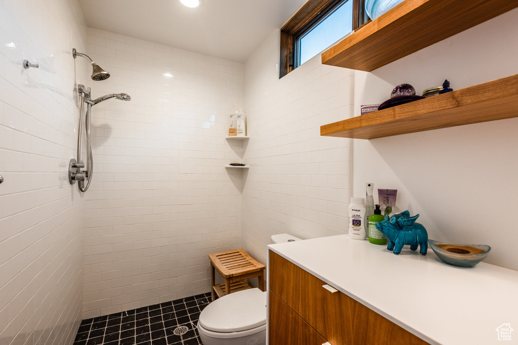 Bathroom featuring toilet, a tile shower, and vanity