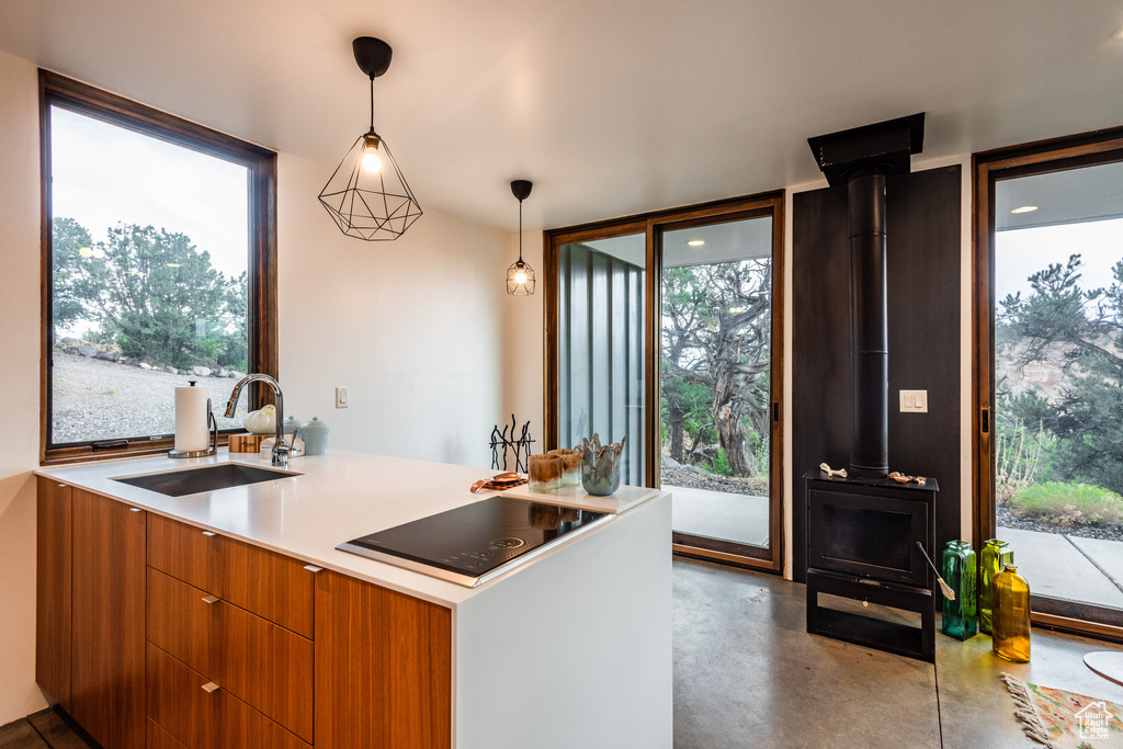 Kitchen featuring a wealth of natural light, sink, a wood stove, and hanging light fixtures