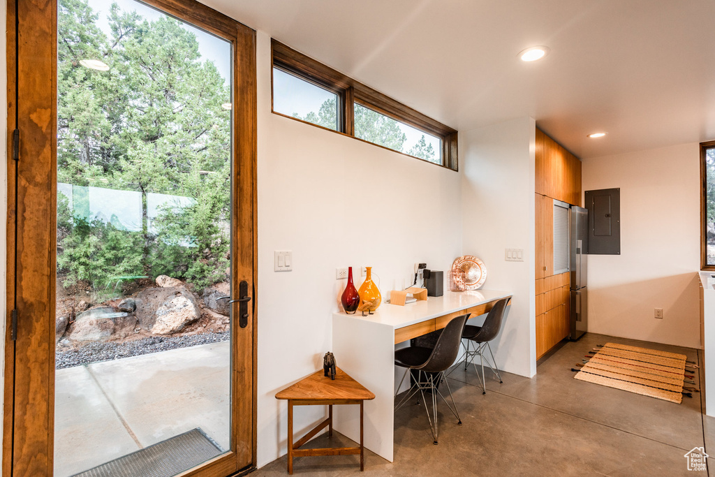 Interior space with stainless steel fridge, concrete floors, and electric panel