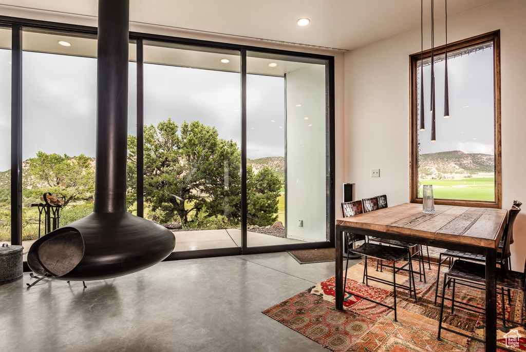 Dining room featuring concrete flooring, a wall of windows, and a healthy amount of sunlight