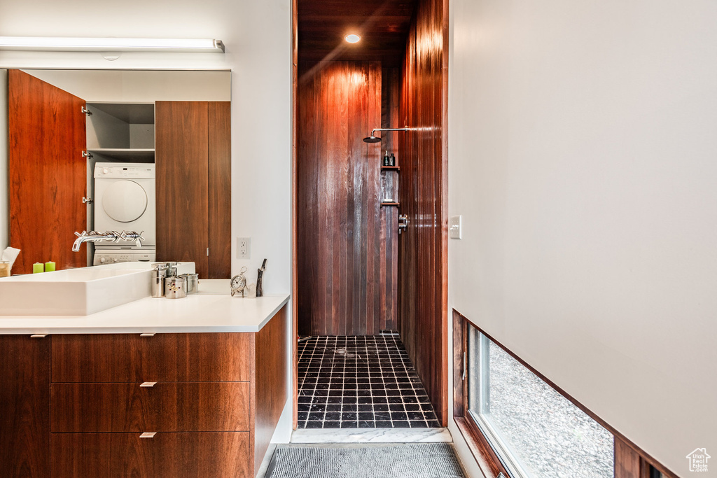 Bathroom featuring stacked washer and dryer, vanity, and tile patterned floors