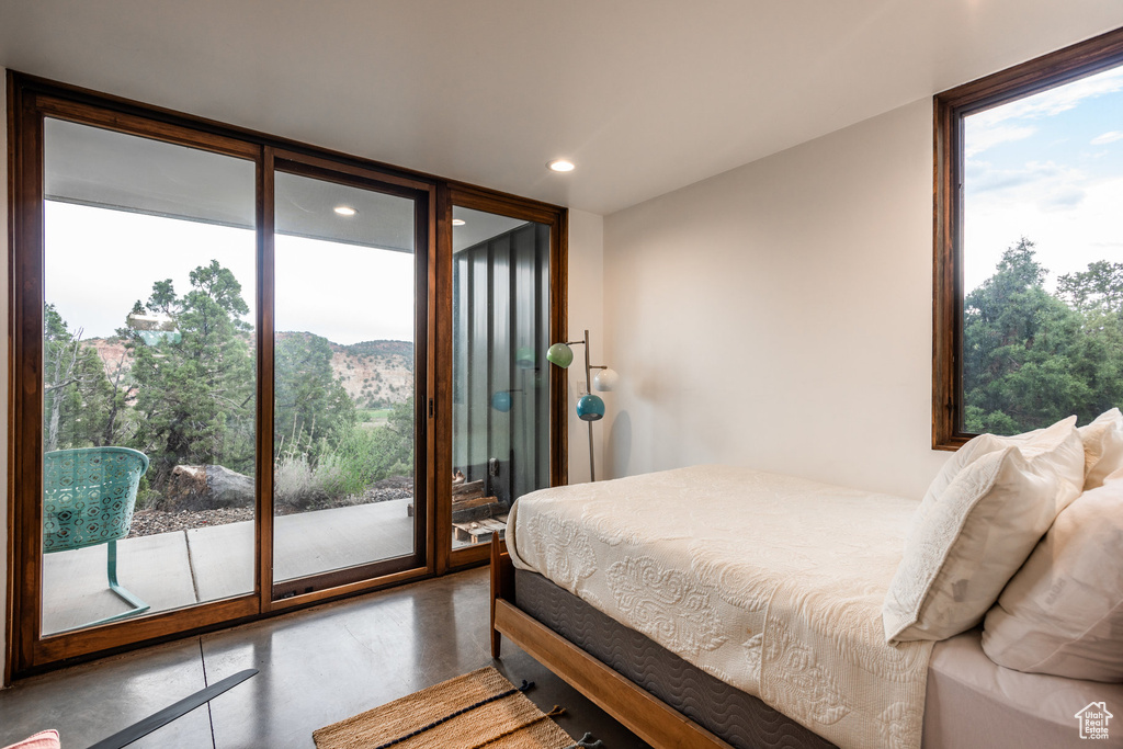 Bedroom with concrete floors, expansive windows, and access to exterior