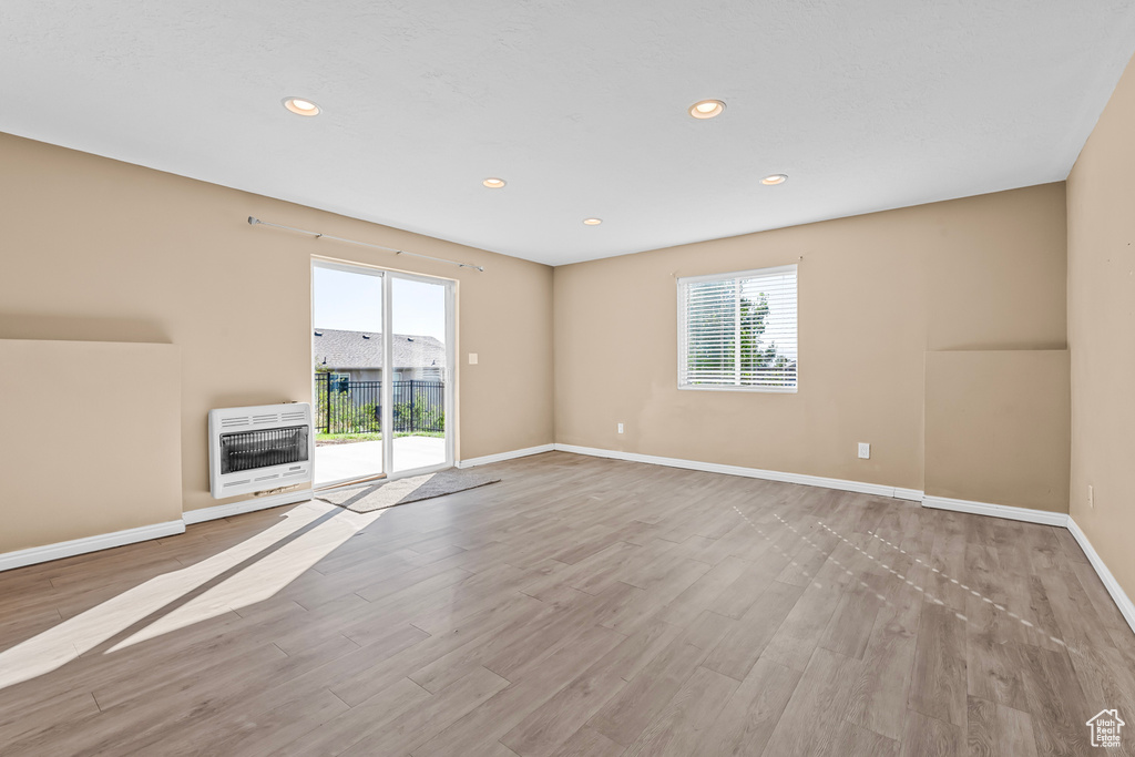 Unfurnished room featuring heating unit and light hardwood / wood-style flooring