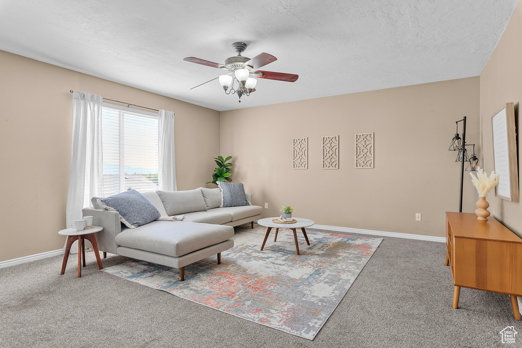 Carpeted living room with ceiling fan and a textured ceiling