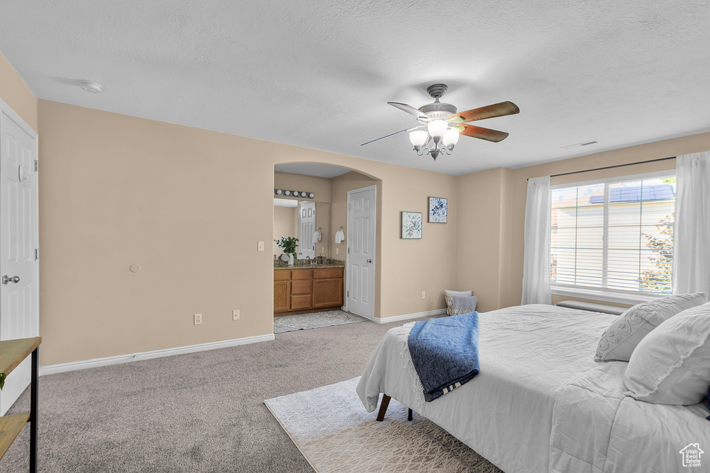 Carpeted bedroom featuring ceiling fan and ensuite bathroom