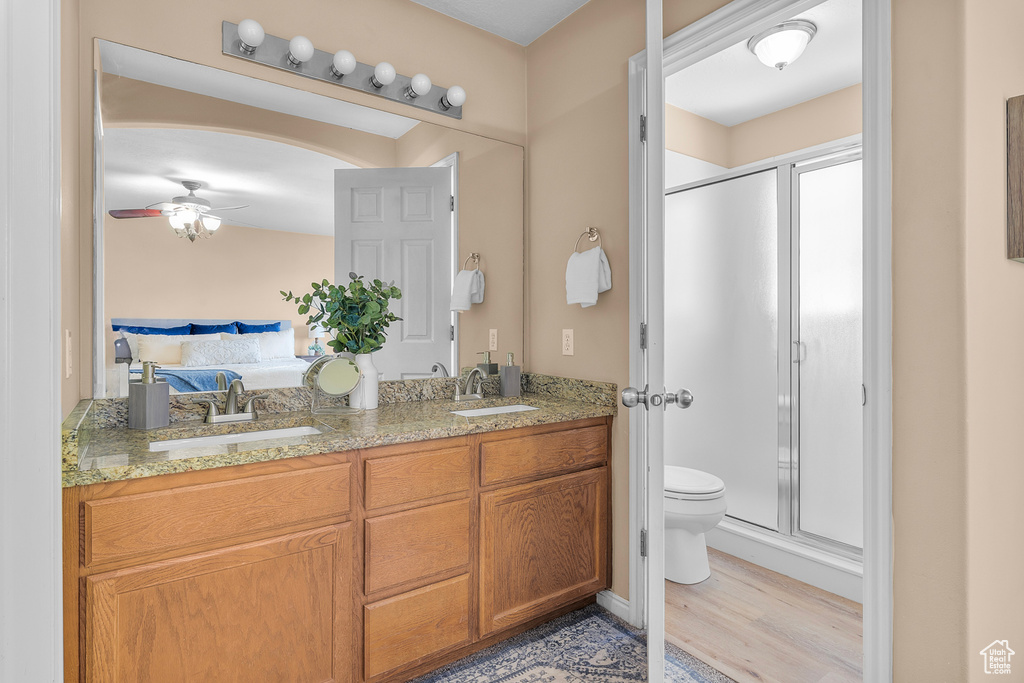 Bathroom with hardwood / wood-style flooring, a shower with door, vanity, and toilet