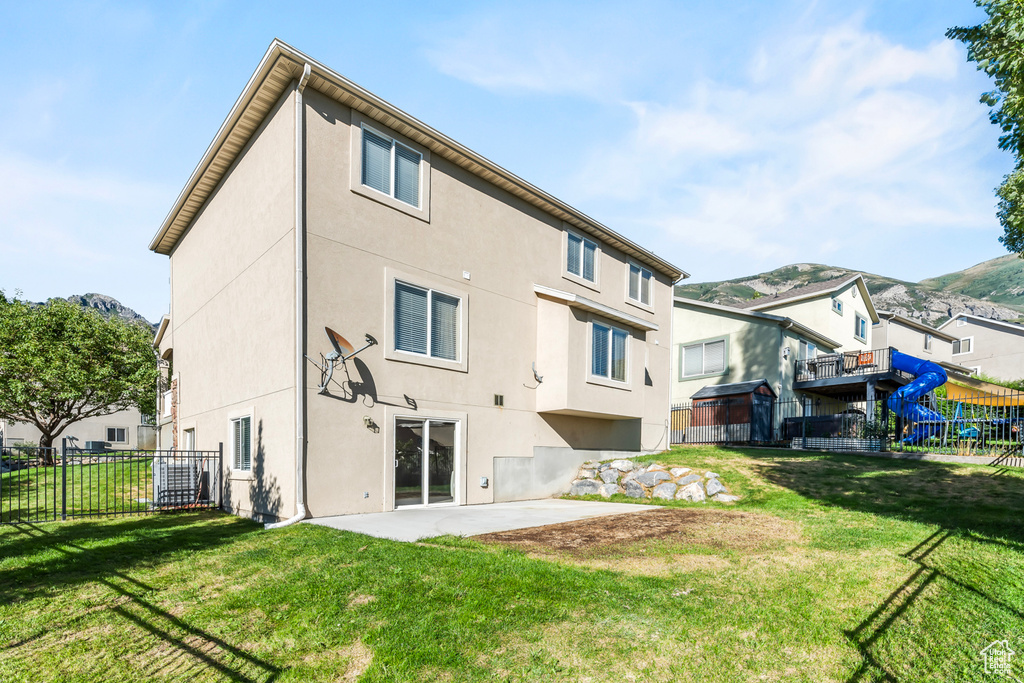 Rear view of property featuring a patio, a playground, and a yard