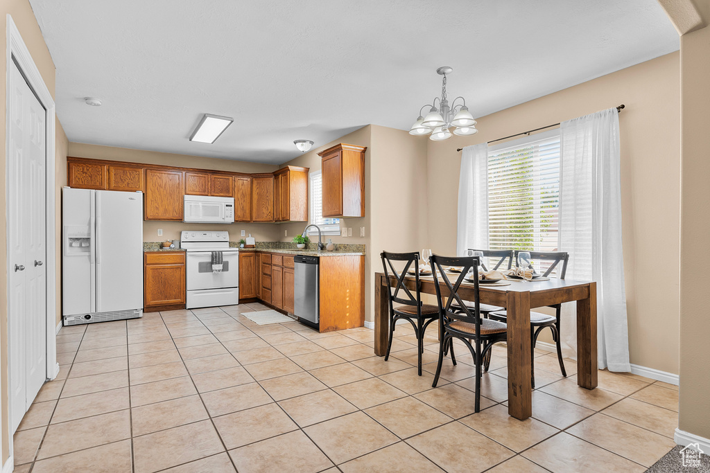 Kitchen featuring a notable chandelier, pendant lighting, white appliances, and light tile patterned floors