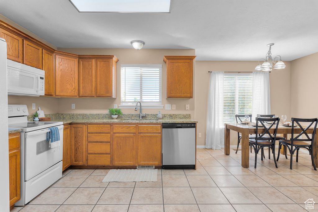 Kitchen with sink, white appliances, light tile patterned flooring, and a healthy amount of sunlight