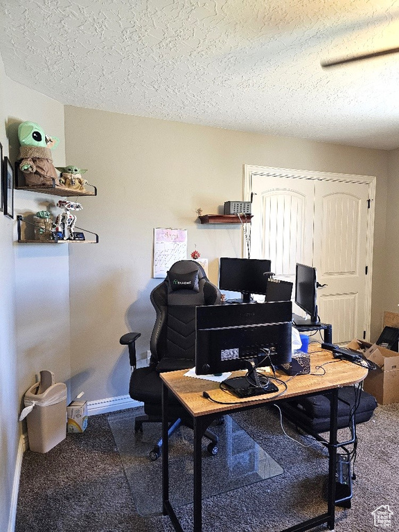 Carpeted home office featuring a textured ceiling