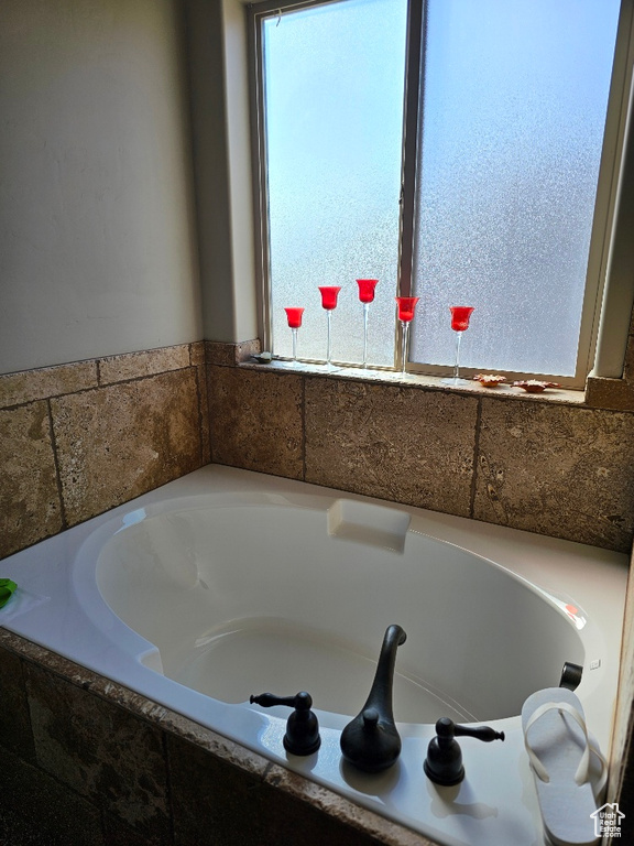 Bathroom with a wealth of natural light and a relaxing tiled tub