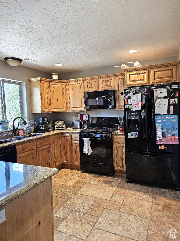 Kitchen with light tile patterned flooring, sink, light stone countertops, a textured ceiling, and black appliances