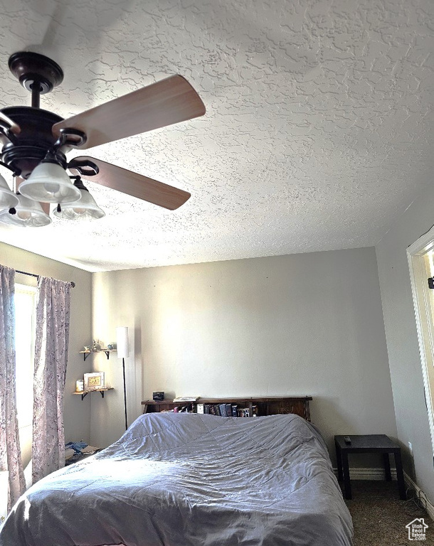 Carpeted bedroom with ceiling fan and a textured ceiling