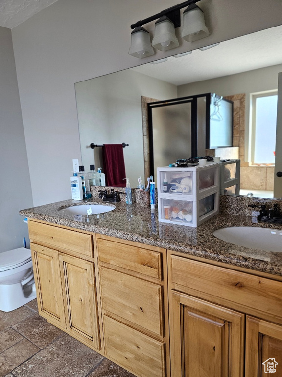 Bathroom featuring toilet, a shower with door, and vanity