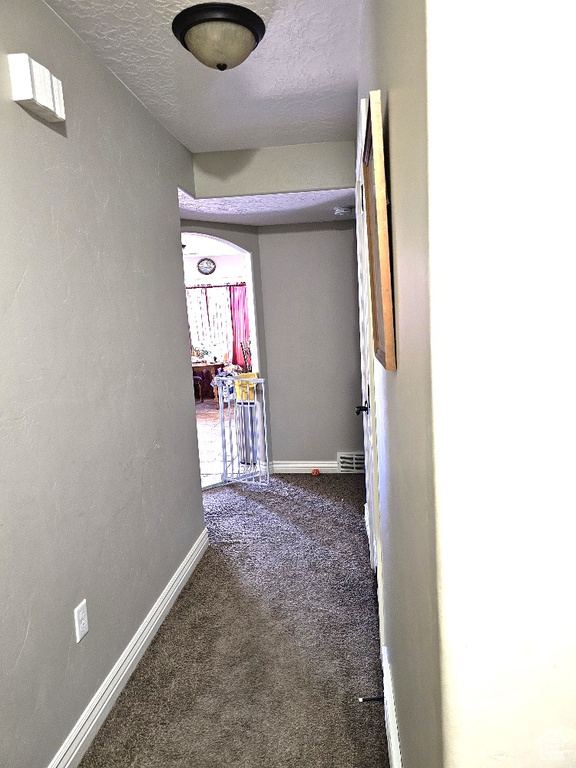 Hall featuring a textured ceiling and carpet floors