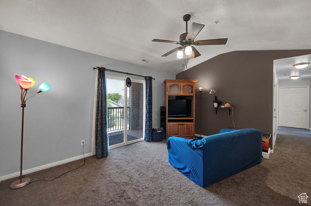 Living room featuring carpet, vaulted ceiling, ceiling fan, and a textured ceiling