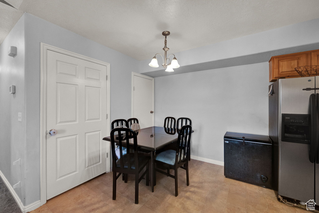 Dining room with light tile patterned floors and a notable chandelier