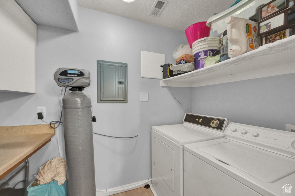 Laundry area featuring a textured ceiling, electric panel, and washer and dryer