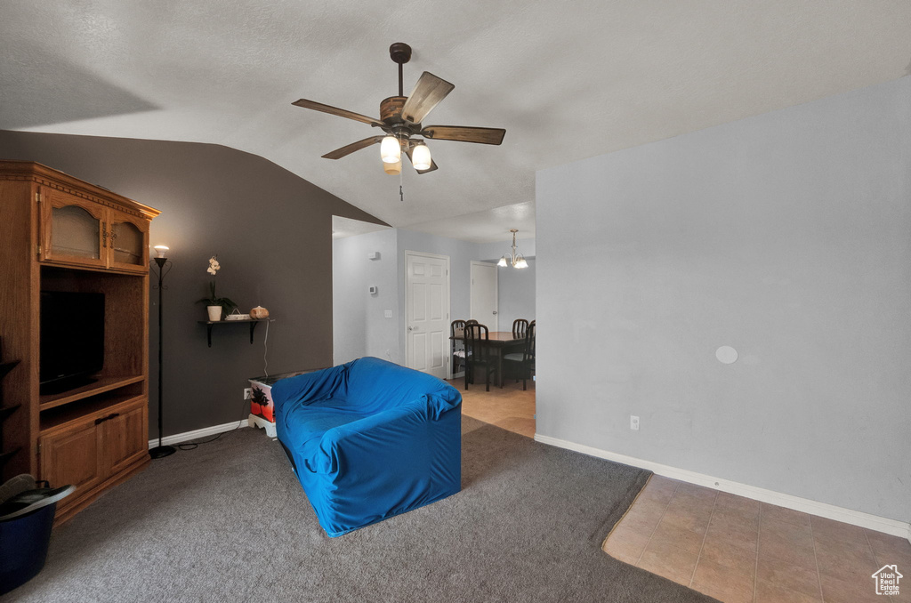 Living area featuring ceiling fan, light tile patterned flooring, and lofted ceiling