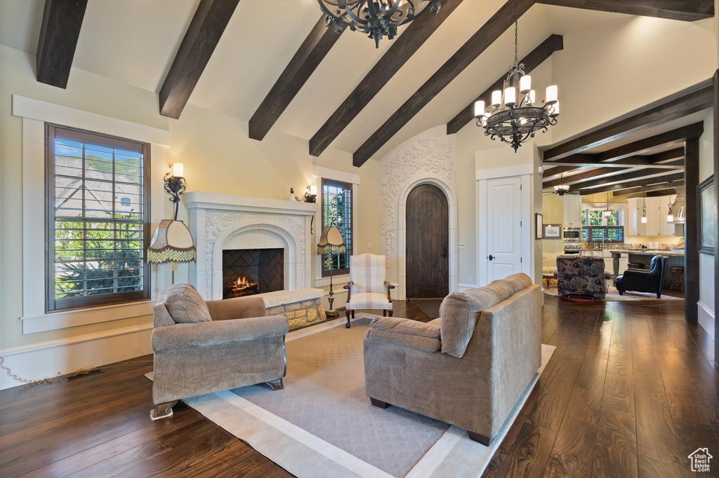 Living room with beamed ceiling, high vaulted ceiling, dark wood-type flooring, and an inviting chandelier