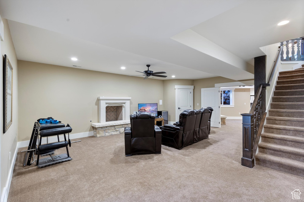 Living room with a fireplace, ceiling fan, and light carpet