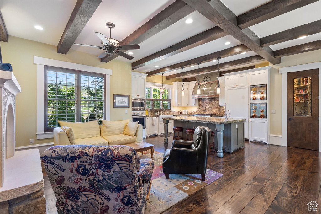 Living room featuring ceiling fan, beam ceiling, and dark wood-type flooring