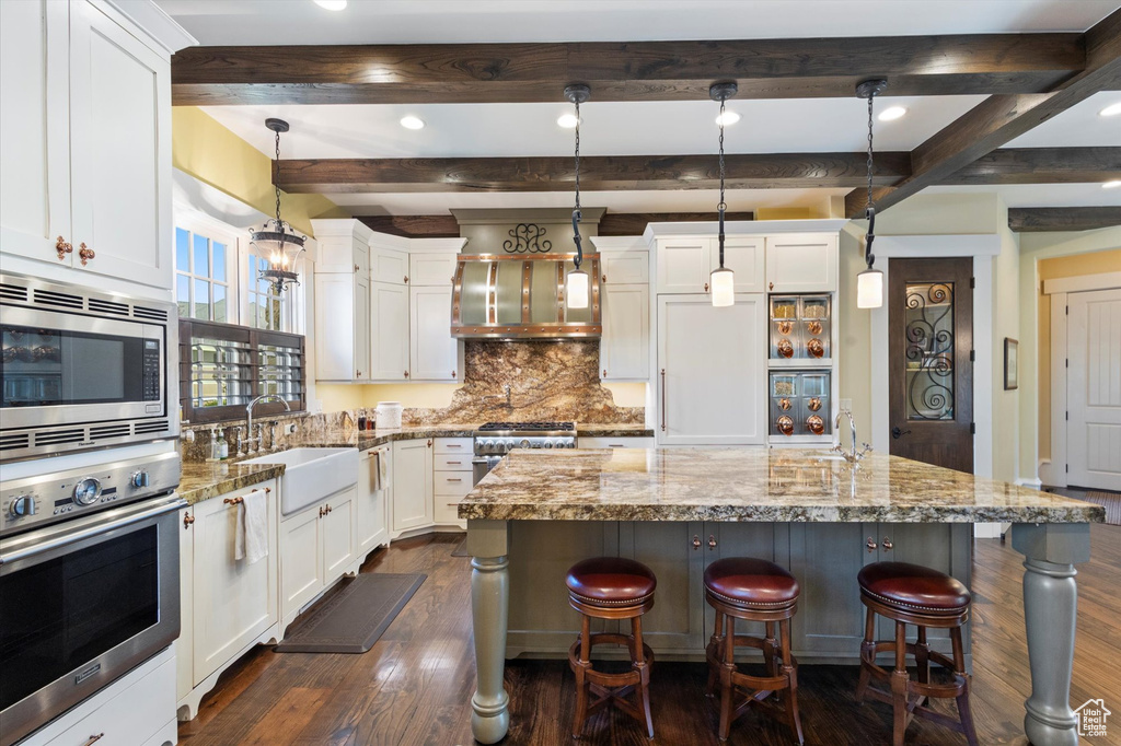 Kitchen featuring stainless steel appliances, hanging light fixtures, tasteful backsplash, and light stone countertops